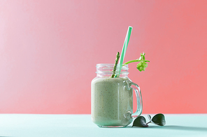 Vegetarian healthy mix from vegetables with green leaves and plastic straw in a glass jar on duotone background in a color of the year 2019 Living Coral Pantone.