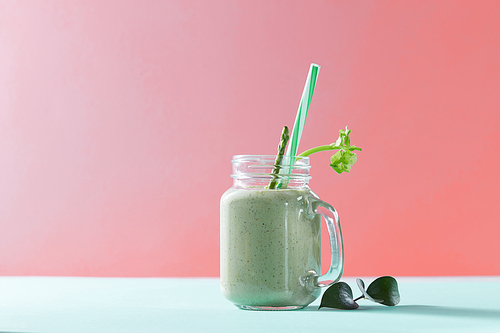 Vegetarian healthy mix from vegetables with green leaves and plastic straw in a glass jar on duotone background in a color of the year 2019 Living Coral Pantone.