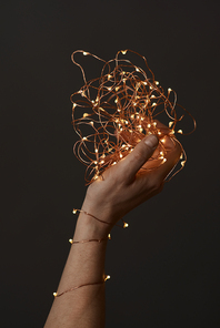 beautiful christmas lights garland in a female hand on a dark background