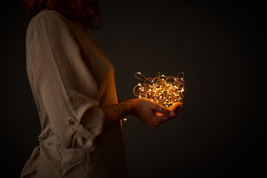 Young girl holding yellow garland lights in the dark