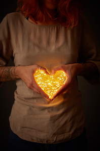 girl with a tattoo on her hands holds a garland in the shape of a heart
