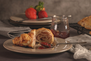 Baked croissants with strawberry jam on a kitchen countertop.