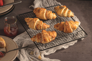 Baked croissants with strawberry jam on a kitchen countertop.