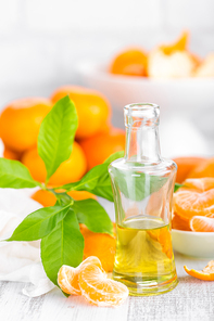 Tangerines with leaves and bottle of essential citrus oil on a white background