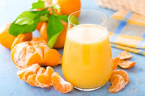 Tangerines, peeled tangerines and tangerine juice in glass. Mandarine juice and fresh fruits with leaves.