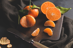 Fresh mandarin oranges or tangerines with leaves on textured dark background