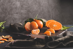 Fresh mandarin oranges or tangerines with leaves on textured dark background