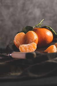 Fresh mandarin oranges or tangerines with leaves on textured dark background