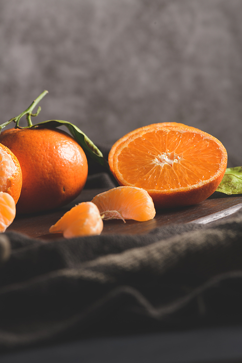 Fresh mandarin oranges or tangerines with leaves on textured dark background