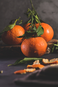 Fresh mandarin oranges or tangerines with leaves on textured dark background