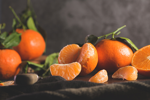 Fresh mandarin oranges or tangerines with leaves on textured dark background