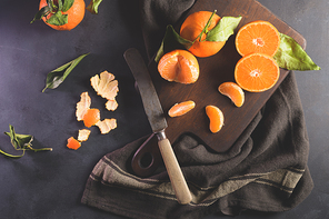 Fresh mandarin oranges or tangerines with leaves on textured dark background