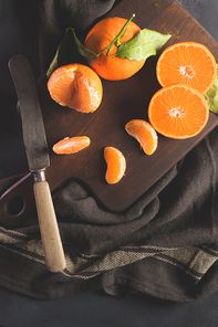 Fresh mandarin oranges or tangerines with leaves on textured dark background