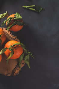 Fresh mandarin oranges or tangerines with leaves on textured dark background