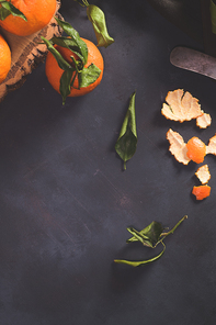 Fresh mandarin oranges or tangerines with leaves on textured dark background