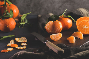 Fresh mandarin oranges or tangerines with leaves on textured dark background