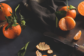 Fresh mandarin oranges or tangerines with leaves on textured dark background