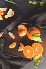 Fresh mandarin oranges or tangerines with leaves on textured dark background