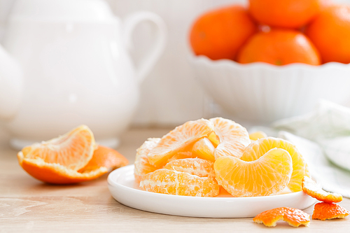 Tangerines. Sweet tasty peeled tangerines on plate on white kitchen background closeup. Healthy and delicious vegan, vegetarian food.