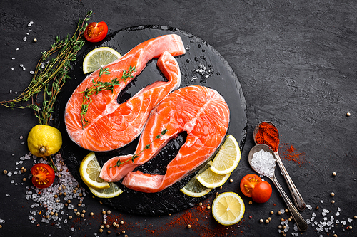 Fresh raw salmon red fish steaks on black background, top view