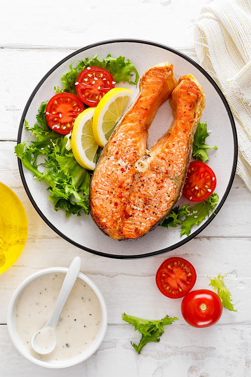 salmon fish steak grilled and fresh  salad with tomato and lettuce. healthy food. top view