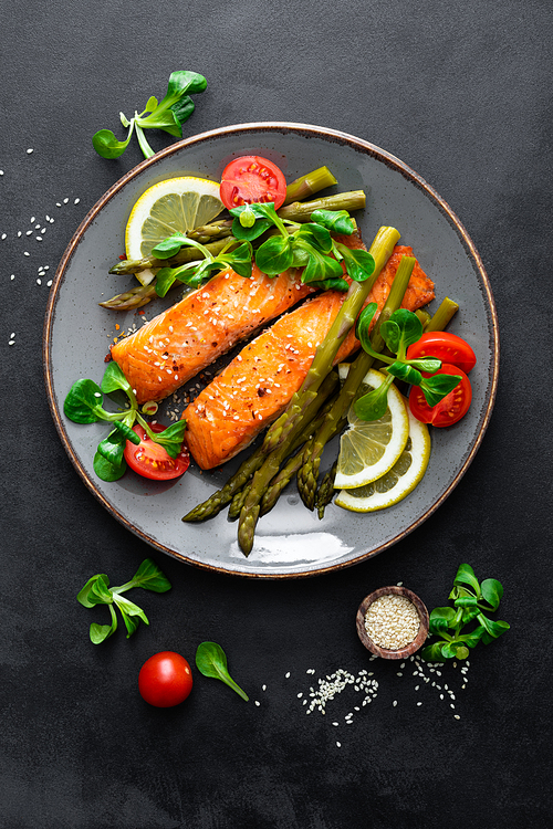 Grilled salmon fish steak, asparagus, tomato and corn salad on plate. Healthy dish for lunch. Top view