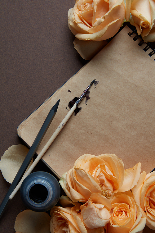 Closeup of diary or notebook covered by orange roses for your notes. flat lay