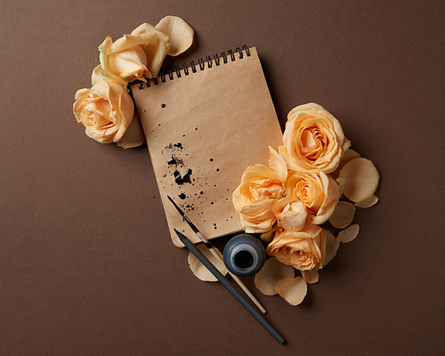 Diary or notebook with yellow roses around for ideas and expressing emotions. Blank copy space for writing congratulations., flat lay