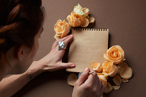 Woman writing love sign in notepad with orange roses