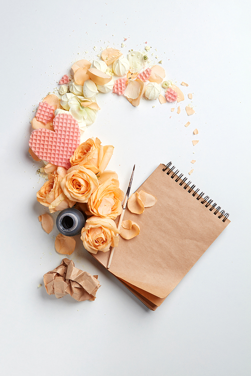 Inkwell with a notebook and a heart with flowers on a white background with space for text