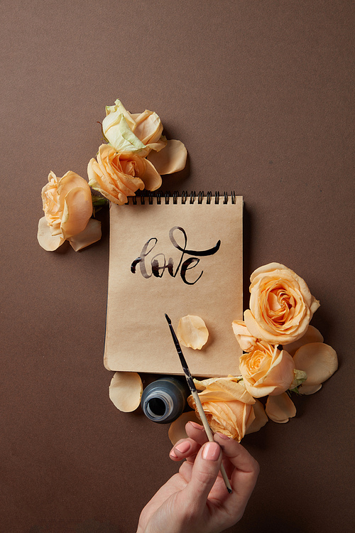 The girl writes a congratulation love on a brown background with roses