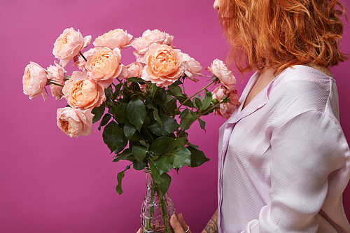 A girl is holding a large bouquet of pink roses media of a media view from the back on a purple background. Mother's Day