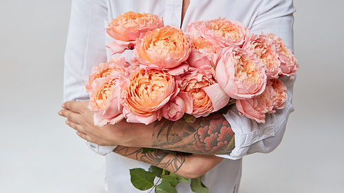 woman with a tattoo on her hands holding a bouquet of pink roses, valentine's day