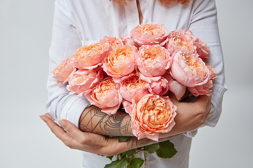 a bouquet of pink roses a woman with a tattoo is holding in her hands. The valentine's day