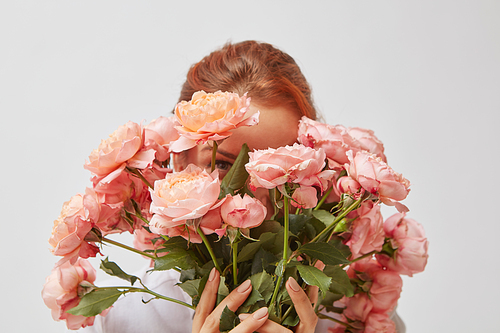 Beautiful pink bouquet of roses. A young girl hides her face behind a bouquet of flowers. St. Valentine's Day. Women's Day
