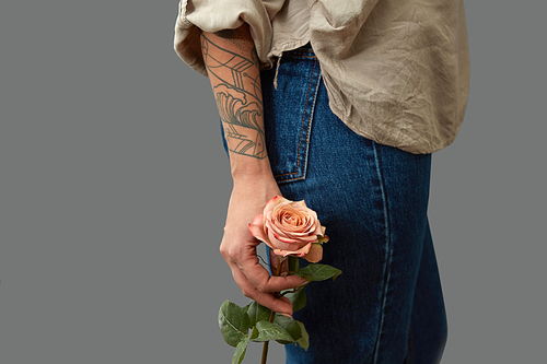 A fragrant flower is holding a female hand with a tattoo around a dark background with copy space. Postcards for Mother's Day
