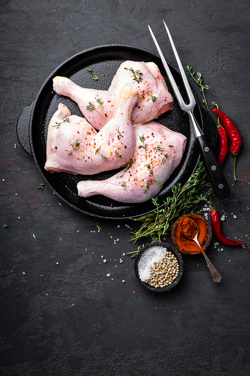 Raw chicken quarters, legs in a pan on a dark background. Top view.