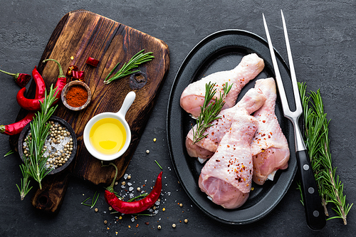 Chicken legs, drumsticks and ingredients for cooking, raw meat on black background, top view