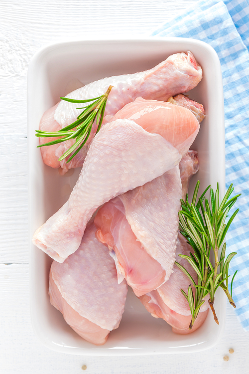 Raw chicken legs, fresh poultry drumsticks on white wooden table, top view
