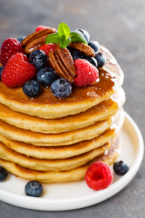Stack of fluffy pancakes with fresh berries and pecan nuts