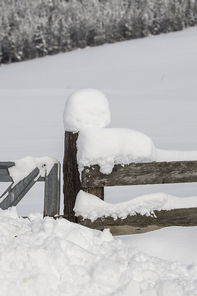 Deep snow covers a wooden fence and a post in north Idaho.