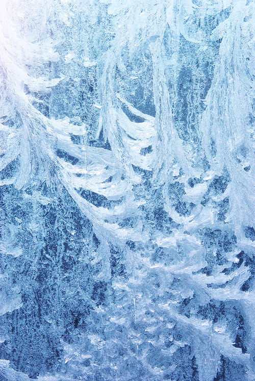 Frost rime patterns on window glass in winter. Frosted Glass Texture. Blue background.