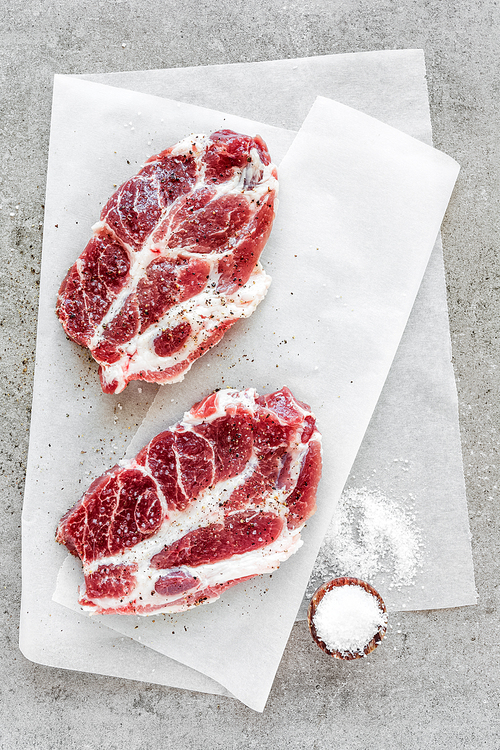 Raw meat steaks on stone background, top view