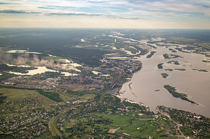 Panoramic view from the drone of landscape with country infrastructure, medows, wide river and large forests on the background of the cloudy sunny sky at sunset.