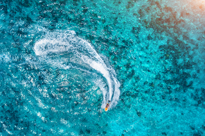 Aerial view of floating water scooter in clear water at sunset in summer. Holiday in Indian ocean, Zanzibar. Top view of jet ski in motion. Tropical seascape with motorboat in blue sea. Extreme