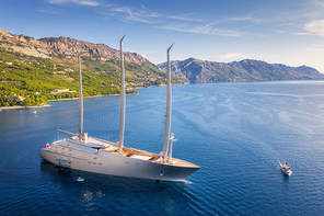 luxury yacht and blue sea at  in summer. aerial view of big modern sail boat. top view of beautiful futuristic yacht, bay, boats, green trees, mountains, clear water, sky. travel in adriatic sea