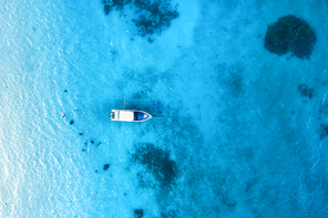aerial view of the white boat in the clear blue water at  in summer. top view from drone of yacht, sandy beach in indian ocean. travel in zanzibar, africa. tropical landscape with motorboat, sea
