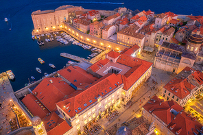 aerial view of boats and yachts and beautiful architecture at night in dubrovnik, croatia. top view of old city at . port in the sea, city lights, historical centre, buildings and red roofs