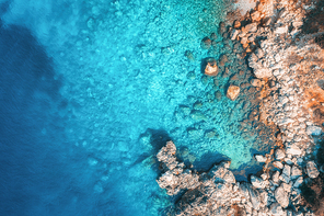 Aerial view of rocky beach and sea with transparent blue water at sunset. Coast of adriatic sea at sunset in summer. Top view. Landscape with clear azure water, stones and rocks. Nature background