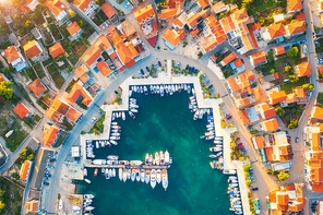 aerial view of boats and yachts in port in old city at . summer landscape with houses with orange roofs, motorboats in harbor, clear blue sea, cars on the road. beautiful architecture. top view